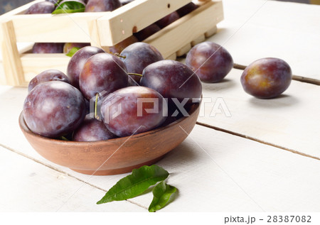 Clay plate with plums closeup 28387082