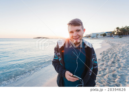 Young man enjoying the music on white sandy beach 28394626