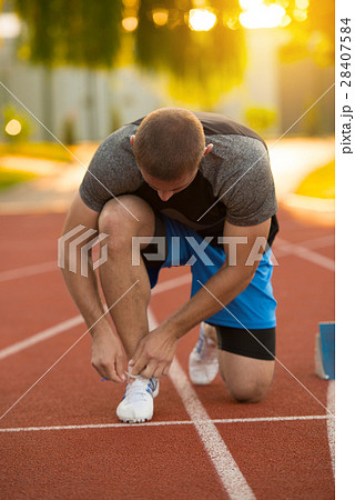 Young Man Runner tying his shoes on a running 28407584