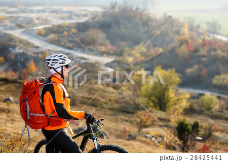 Young bicyclist standing near and looking to 28425441