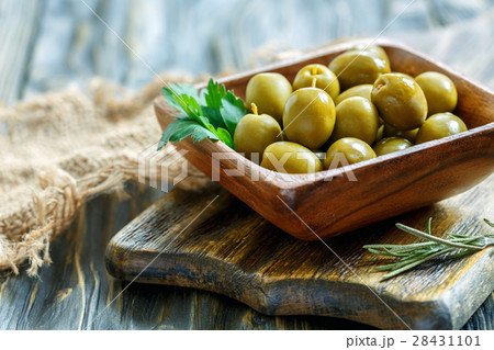 Green olives and parsley in a wooden bowl. 28431101