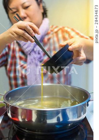 Asia woman cooking by put a flesh egg in to a hot pot Asia woman cooking by put a flesh egg in to a hot pot 28434673