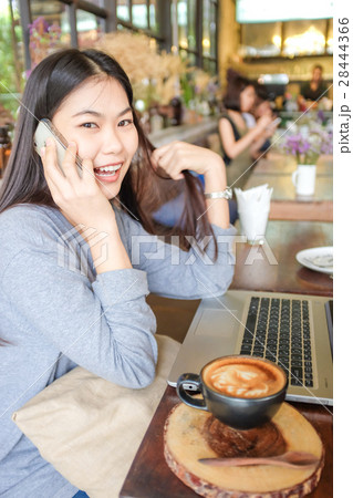Woman at cafe use laptop and talking on phone Woman at cafe use laptop and talking on phone 28444366