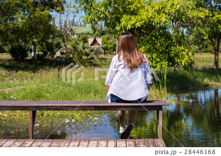 woman enjoying nature on a bench by the pool. 28446168