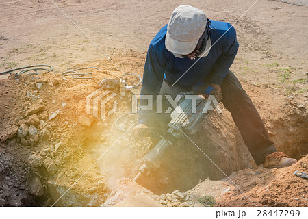 Worker drilling cement concrete floor with machine 28447299