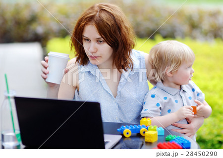 Young mother working oh laptop and holding her son 28450290