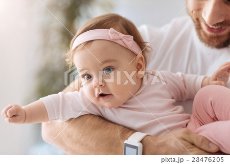 Involved toddler lying in the arms of young father 28476205