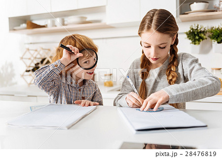 Humorous kid distracting his sister Humorous kid distracting his sister 28476819
