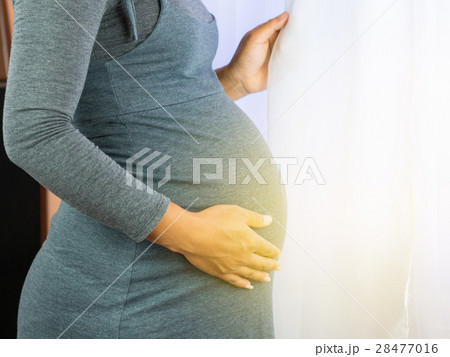 Pregnant Woman standing at window in a sunny day. 28477016