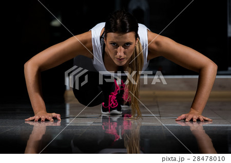 woman in a gym exercising, doing push ups. Dark woman in a gym exercising, doing push ups. Dark 28478010