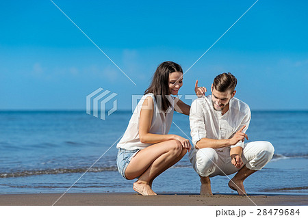 Romantic young couple draw shapes in the sand 28479684