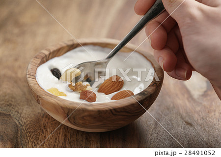 eating with spoon homemade yogurt with muesli in wood bowl on wooden table 28491052
