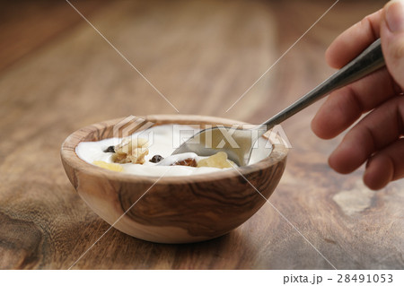 eating with spoon homemade yogurt with muesli in wood bowl on wooden table 28491053
