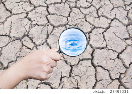 hand holding magnifying find water drop on dry cra hand holding magnifying find water drop on dry cra 28492331