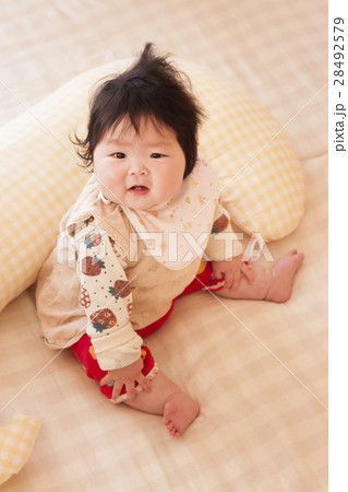 授乳クッションの前で座る赤ちゃん 28492579
