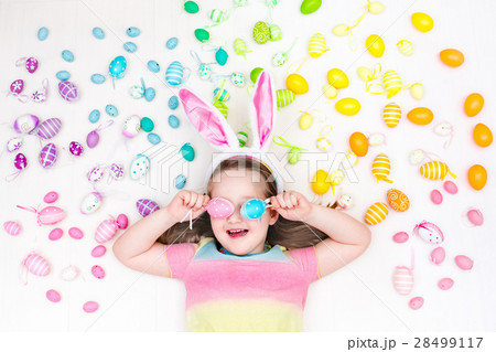 Child on Easter egg hunt. Pastel rainbow eggs. 28499117