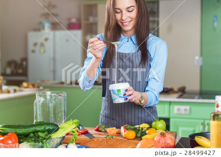 Cheerful young female chef cooking dessert adding Cheerful young female chef cooking dessert adding 28499427