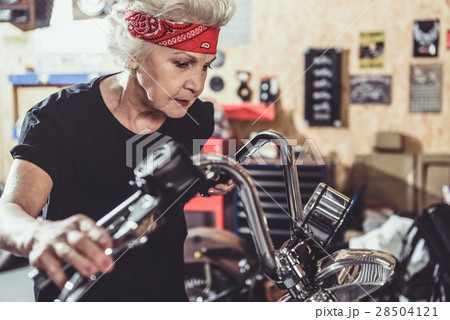 Serene female retiree situating near motorcycle Serene female retiree situating near motorcycle 28504121