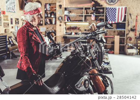 Serene granny situating next to bike in garage Serene granny situating next to bike in garage 28504142