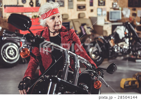 Pensive retiree locating on bike in mechanic shop Pensive retiree locating on bike in mechanic shop 28504144