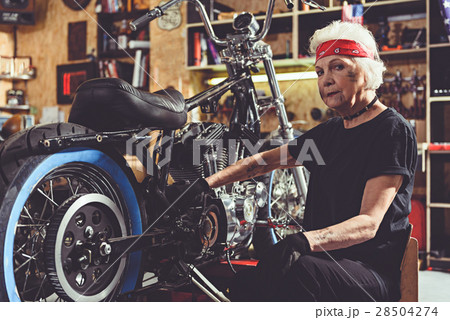 Serious retiree repairing bike in mechanic shop Serious retiree repairing bike in mechanic shop 28504274