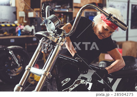 Serene granny reconditioning motorcycle in garage 28504275