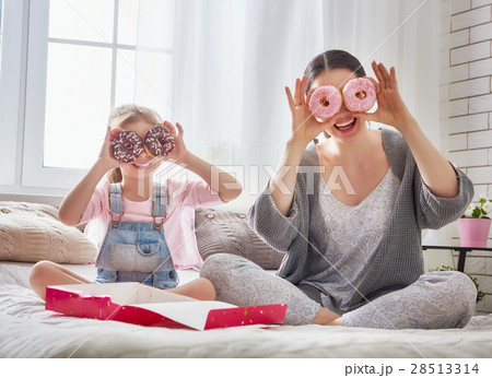 Mother and her daughter eating donuts 28513314