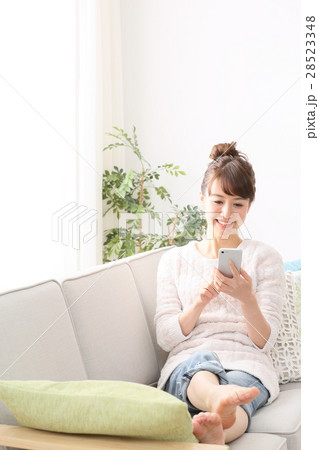 ソファーでスマホを使う女性　 28523348