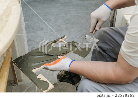 Worker puts the adhesive on the tile. Worker puts the adhesive on the tile. 28529265
