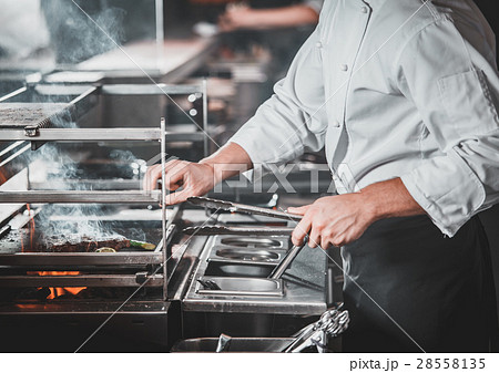 Busy chef at work in the restaurant kitchen Busy chef at work in the restaurant kitchen 28558135