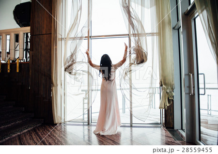 beautiful woman opens the curtains in the house 28559455