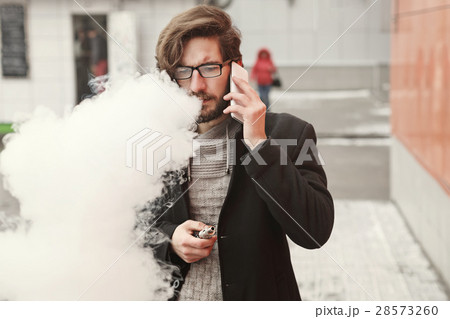 Man with e-cigarette and cell phone 28573260