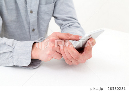 スマホを持つ若い男性 白バックの写真素材