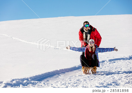 Young playful couple having fun sledging down snow 28581898