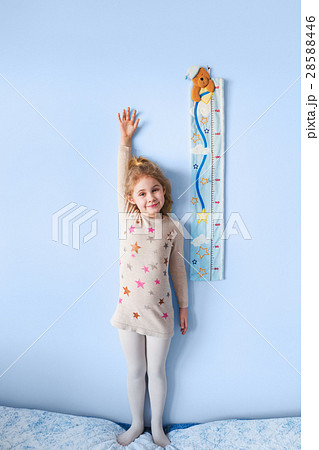 Little blonde girl measuring height against wall 28588446