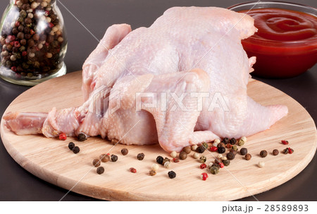 raw chicken carcass with peppercorns on a dark 28589893
