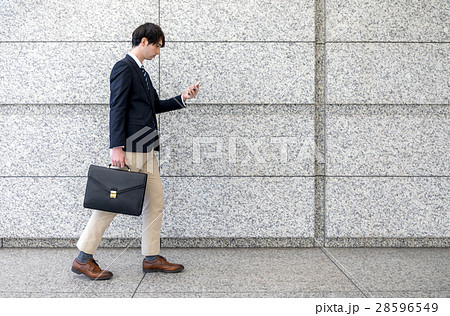 スマホを見ながら歩く男性の写真素材