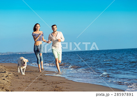 Portrait of a happy couple with dogs at the beach Portrait of a happy couple with dogs at the beach 28597891