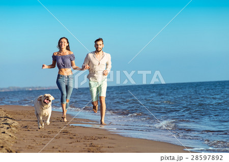 Portrait of a happy couple with dogs at the beach Portrait of a happy couple with dogs at the beach 28597892