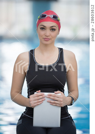 Fit female swimming trainer with tablet at the 28603612