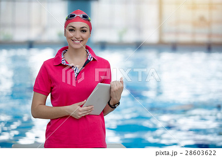 Fit female swimming trainer with tablet at the 28603622