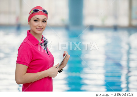 Fit female swimming trainer with tablet at the 28603818