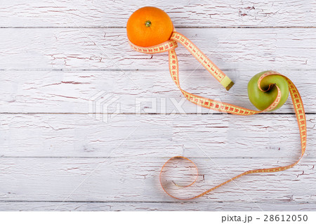 The green apple and orange stand near centimeter 28612050