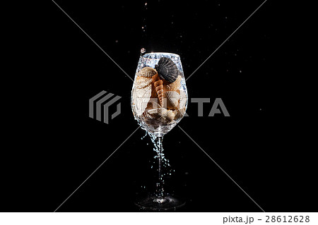 Water falls in wineglass full of shells 28612628