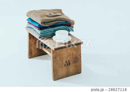 Stack of winter sweaters  and cafe on rustic bench 28627118