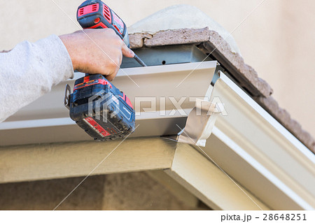 Worker Attaching Aluminum Rain Gutter a House. Worker Attaching Aluminum Rain Gutter a House. 28648251