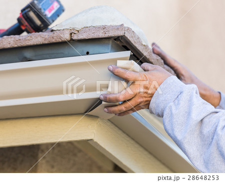 Worker Attaching Aluminum Rain Gutter a House. Worker Attaching Aluminum Rain Gutter a House. 28648253