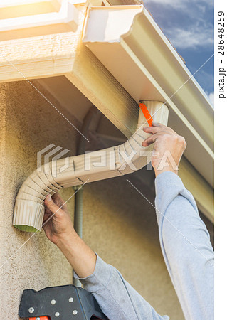 Worker Attaches Aluminum Rain Gutter Down Spout Worker Attaches Aluminum Rain Gutter Down Spout 28648259