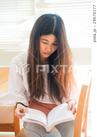Woman sitting on wood chair holding book to read Woman sitting on wood chair holding book to read 28676177