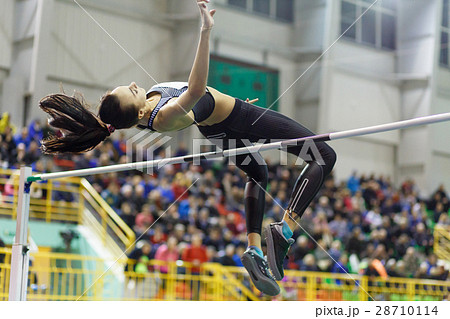 Young girl jumping over bar in high jump contest. 28710114